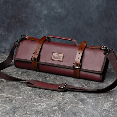 Maroon leather knifebag with adjustable straps on a stone gray surface