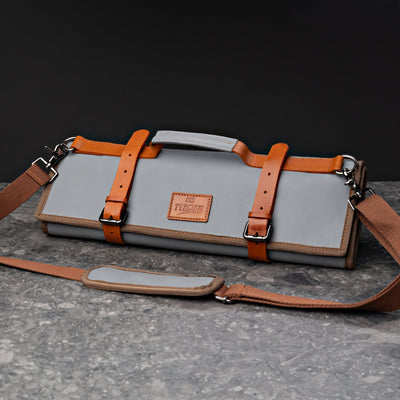 ITAMAE Osaka Knifebag in gray leather with tan straps, rolled and buckled with shoulder strap for professional chefs on the move.